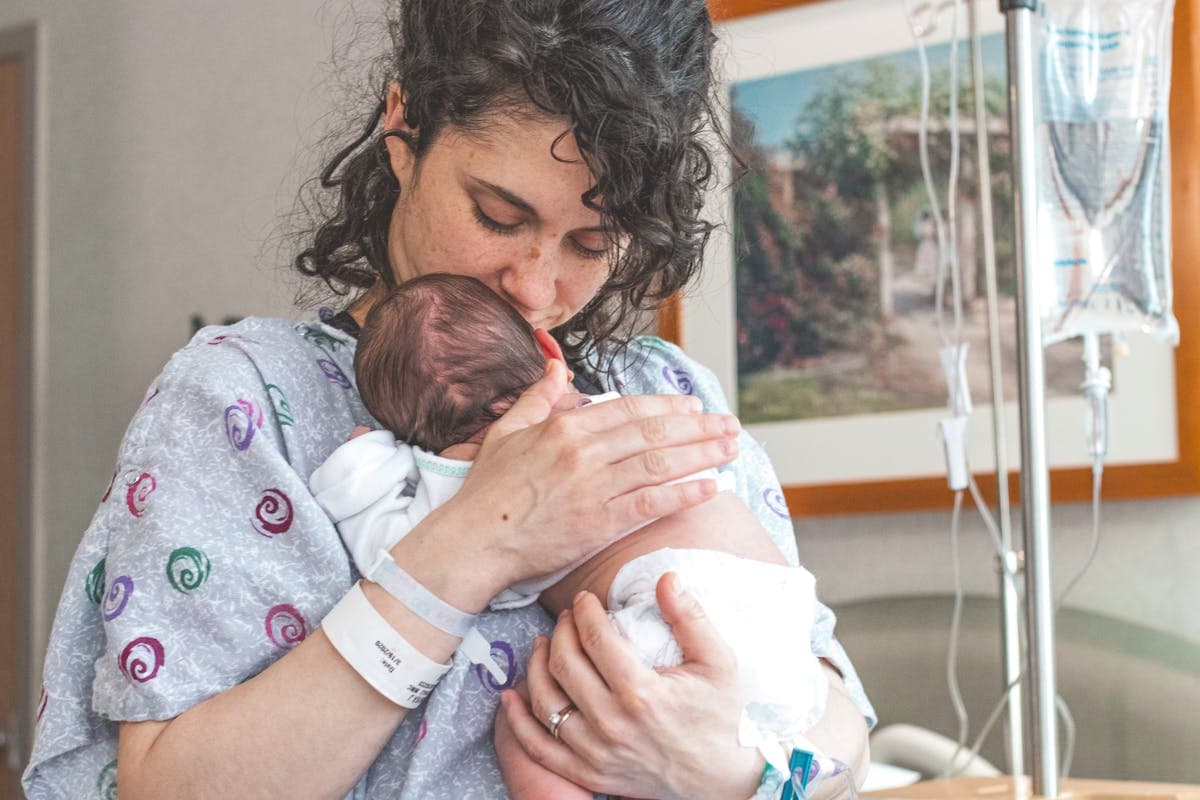Mother gently holding a newborn baby in a hospital setting after delivery
