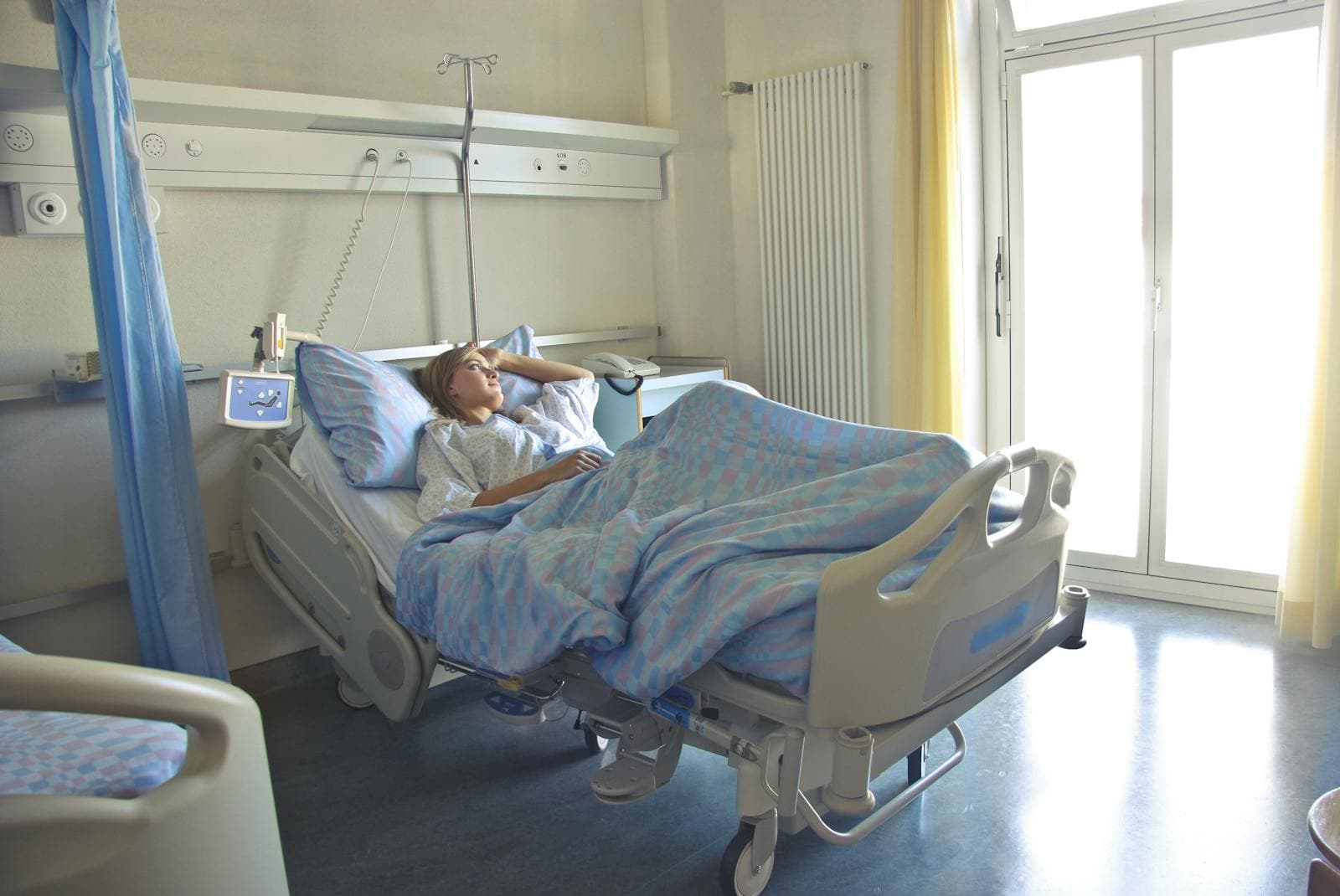 Woman resting comfortably in a hospital bed in a softly lit room, representing pain-managed labour