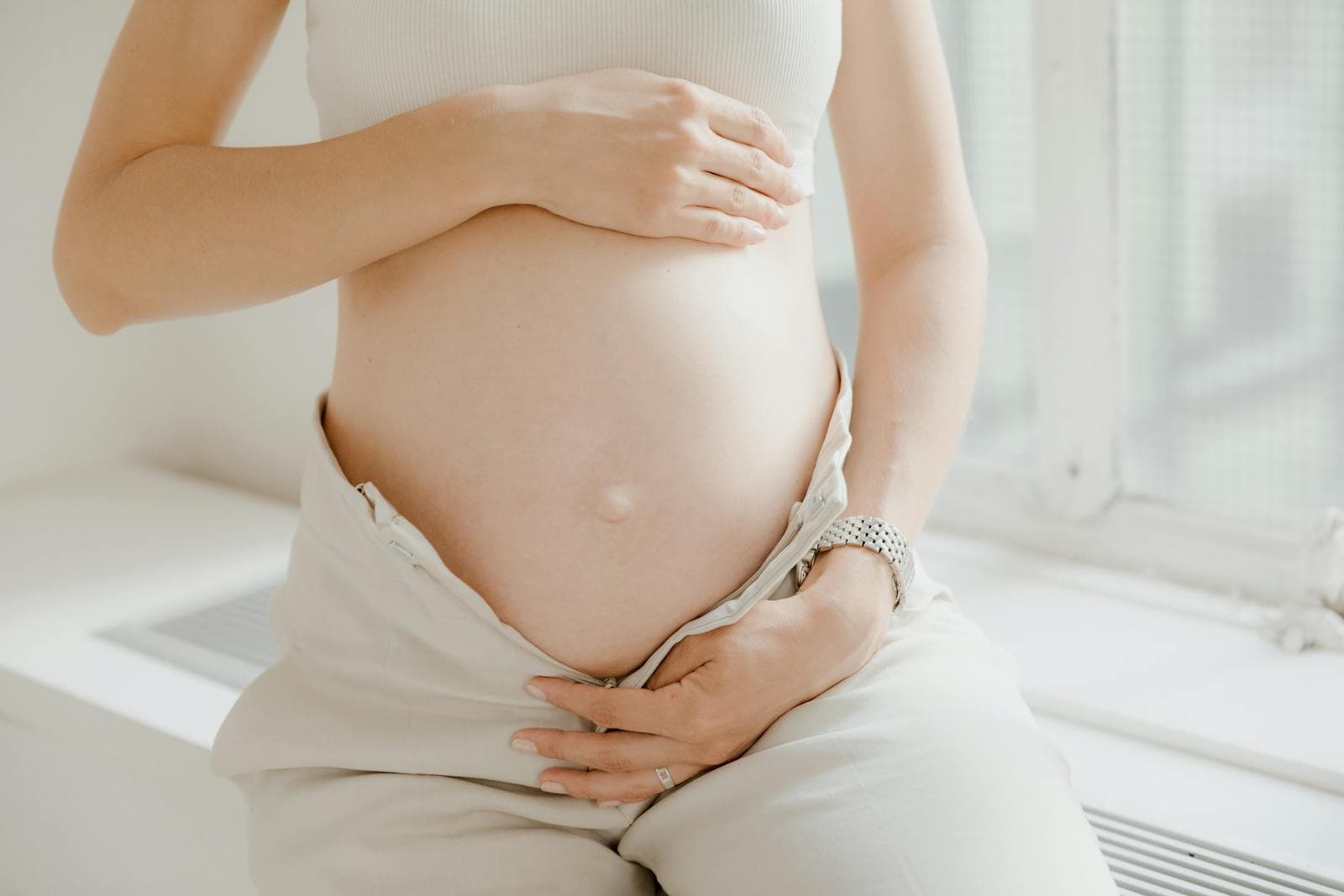 Pregnant woman gently holding her belly, symbolising hope and the journey to conception